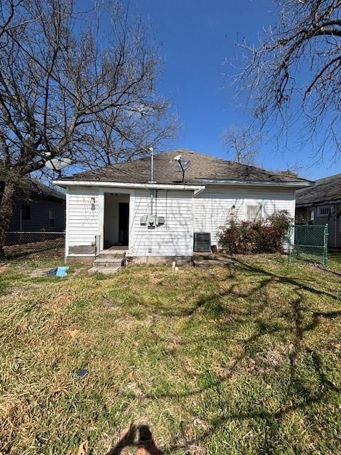 rear view of house featuring a yard, fence, and cooling unit