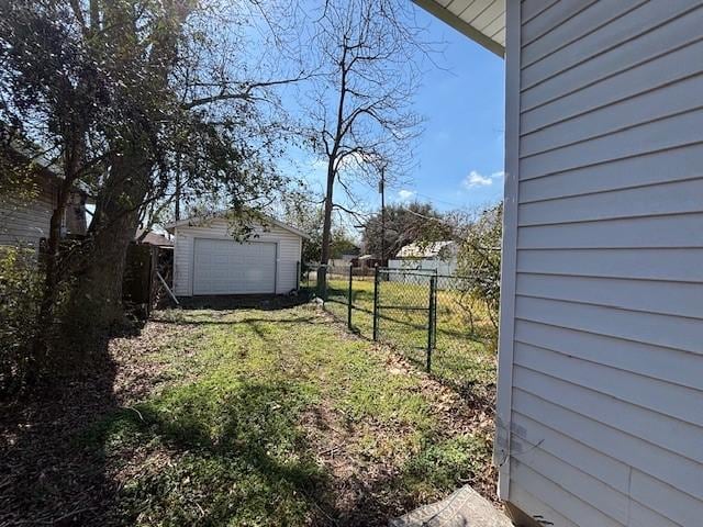 view of yard with a garage, an outdoor structure, driveway, and fence