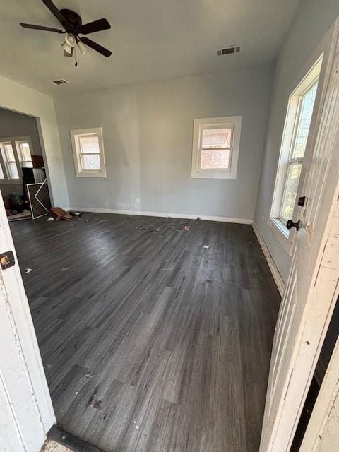 unfurnished room with dark wood finished floors, visible vents, baseboards, and ceiling fan