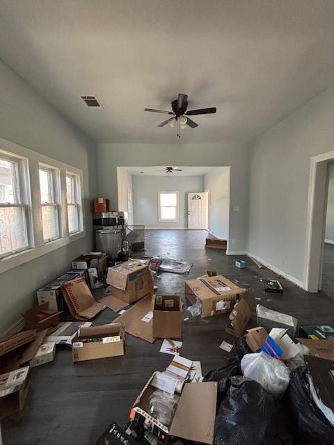 interior space with wood finished floors, visible vents, baseboards, and ceiling fan