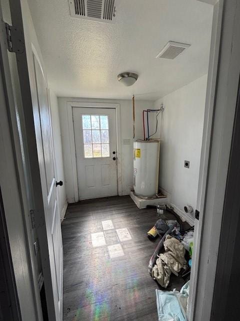 doorway with wood finished floors, visible vents, water heater, and a textured ceiling