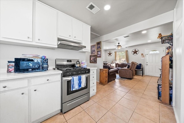 kitchen featuring visible vents, black microwave, under cabinet range hood, light countertops, and gas stove