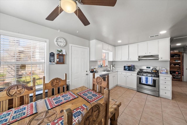 kitchen with visible vents, stainless steel gas range, light tile patterned flooring, light countertops, and under cabinet range hood