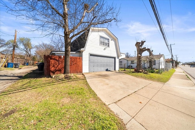 view of side of home with fence, a gambrel roof, concrete driveway, a yard, and a garage