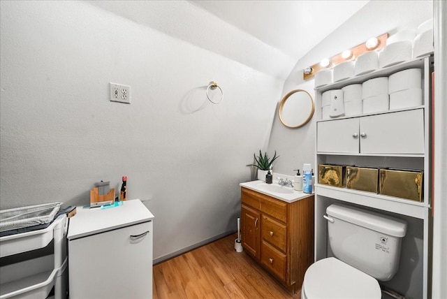 bathroom with vanity, lofted ceiling, toilet, and wood finished floors