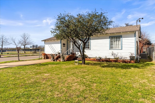 view of front of house featuring entry steps, a front yard, and fence