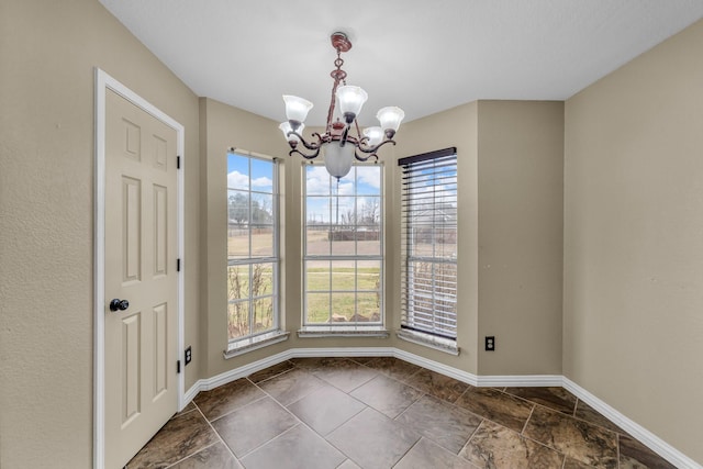 unfurnished dining area featuring baseboards, a wealth of natural light, and a chandelier