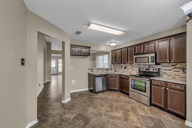 kitchen with baseboards, visible vents, dark brown cabinetry, appliances with stainless steel finishes, and backsplash