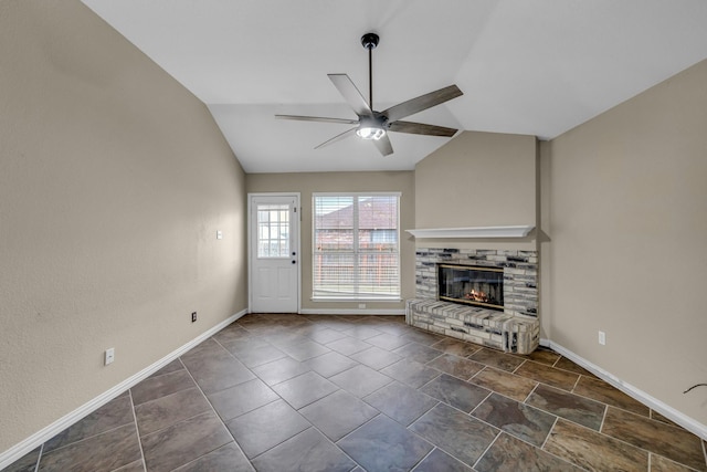 unfurnished living room with lofted ceiling, a brick fireplace, baseboards, and ceiling fan