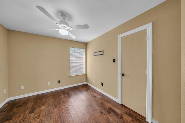 spare room with baseboards, a ceiling fan, and dark wood-style flooring