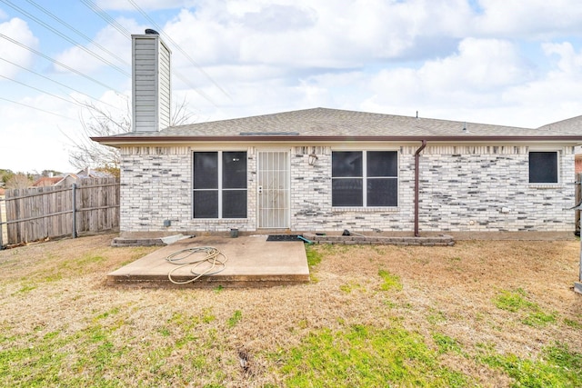 back of house with a patio, a lawn, brick siding, and fence