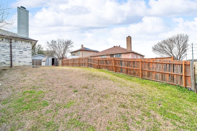 view of yard with an outbuilding, a storage unit, and fence