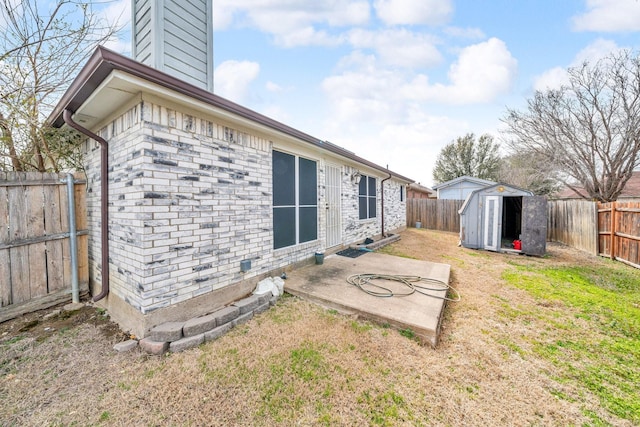 back of property with a patio area, a fenced backyard, brick siding, and an outbuilding