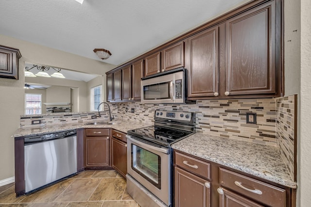 kitchen with a sink, light stone counters, tasteful backsplash, and stainless steel appliances