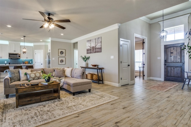 living area featuring baseboards, light wood-style flooring, recessed lighting, ornamental molding, and ceiling fan with notable chandelier