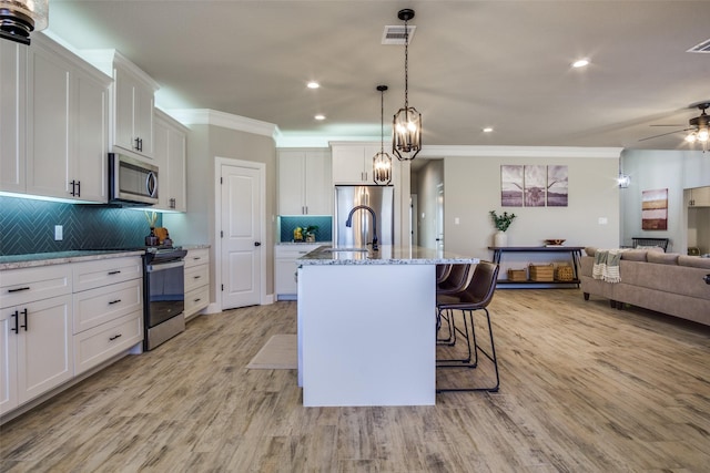 kitchen with visible vents, open floor plan, white cabinetry, stainless steel appliances, and light wood finished floors