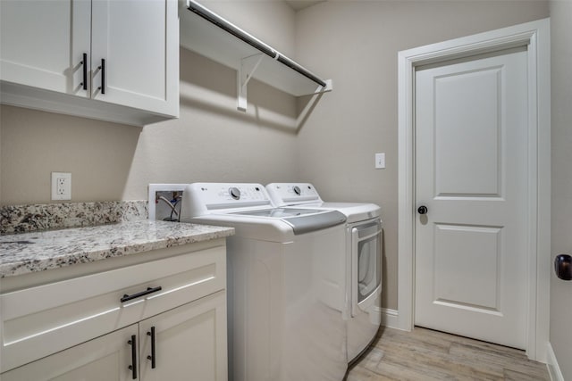 washroom featuring light wood-style flooring, cabinet space, independent washer and dryer, and baseboards