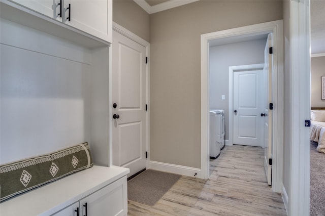 clothes washing area featuring independent washer and dryer, crown molding, light wood finished floors, baseboards, and laundry area