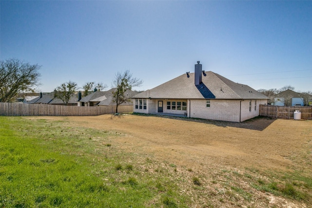 rear view of house with a lawn, a fenced backyard, and a chimney