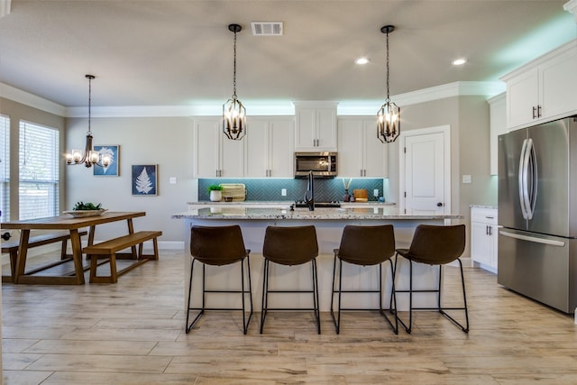 kitchen featuring visible vents, a notable chandelier, backsplash, stainless steel appliances, and crown molding