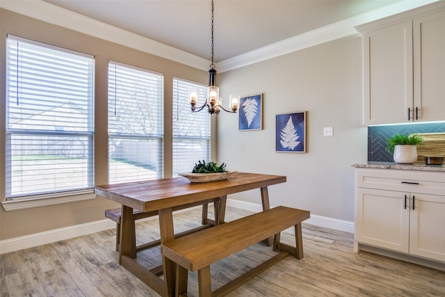 dining space with a notable chandelier, baseboards, light wood-style floors, and ornamental molding