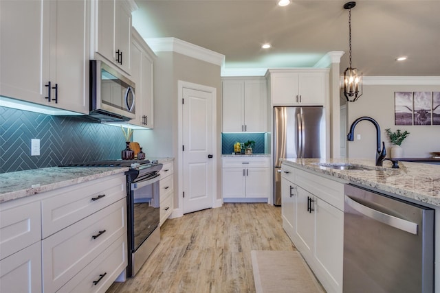 kitchen featuring light wood finished floors, crown molding, appliances with stainless steel finishes, white cabinets, and a sink