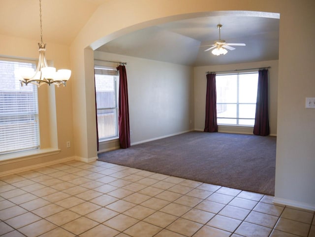 unfurnished room with light carpet, ceiling fan with notable chandelier, arched walkways, light tile patterned floors, and lofted ceiling