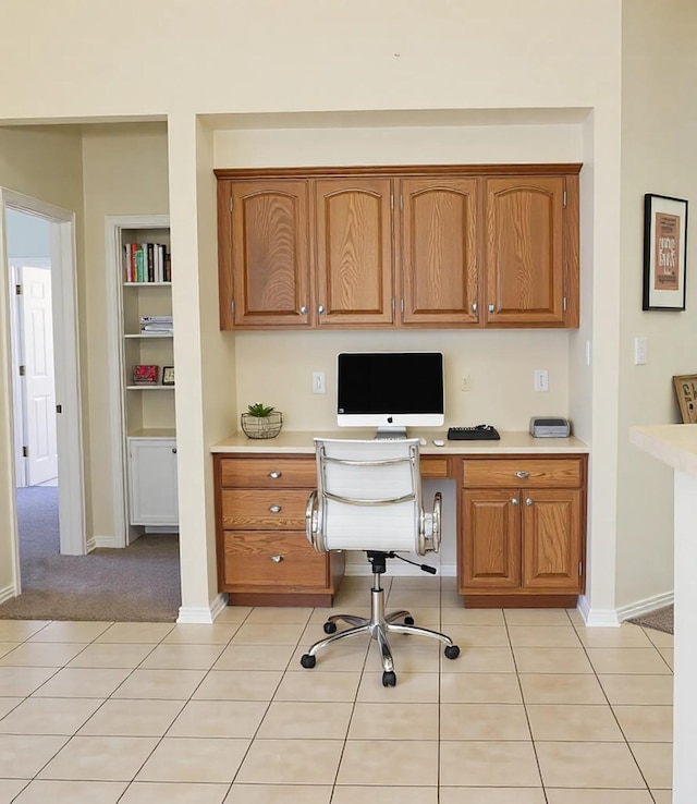 office space featuring built in features, baseboards, light tile patterned flooring, and built in desk