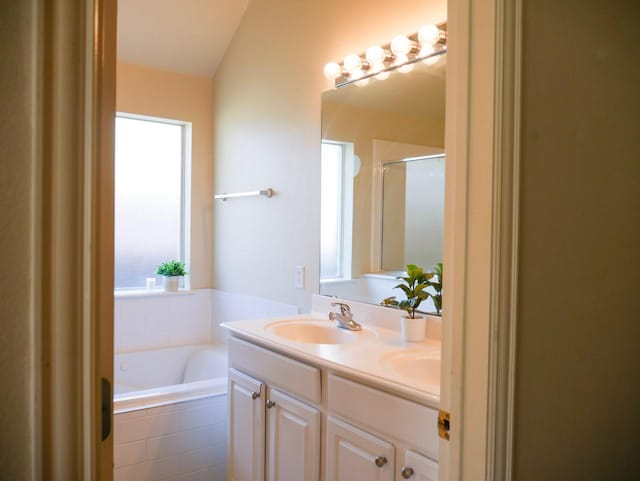 bathroom with double vanity, an enclosed shower, a garden tub, and a sink