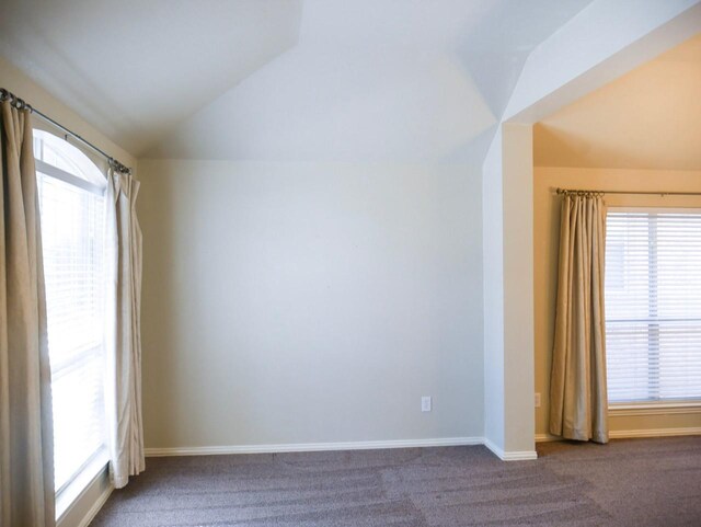 carpeted spare room with baseboards, plenty of natural light, and vaulted ceiling
