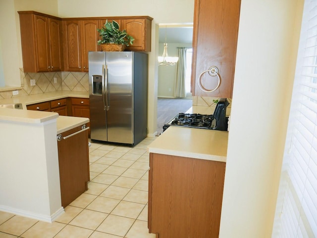 kitchen featuring black range with gas cooktop, light tile patterned floors, stainless steel fridge with ice dispenser, and backsplash