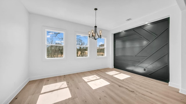 unfurnished dining area with an inviting chandelier, wood finished floors, visible vents, and baseboards