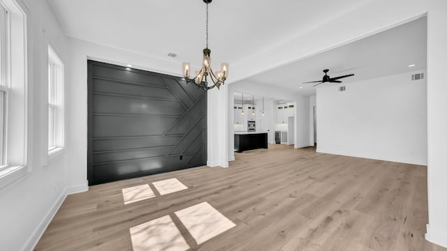 unfurnished dining area featuring visible vents, light wood-style flooring, and a decorative wall