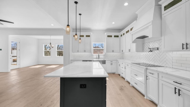 kitchen featuring light wood-type flooring, tasteful backsplash, a center island, black electric stovetop, and custom exhaust hood