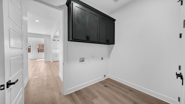 clothes washing area with cabinet space, light wood-style floors, hookup for an electric dryer, and baseboards