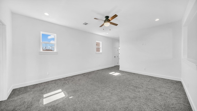 carpeted empty room featuring a wealth of natural light, visible vents, baseboards, and a ceiling fan