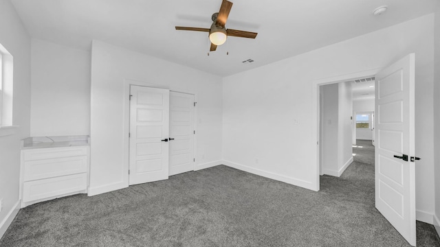 unfurnished bedroom featuring visible vents, dark colored carpet, and baseboards