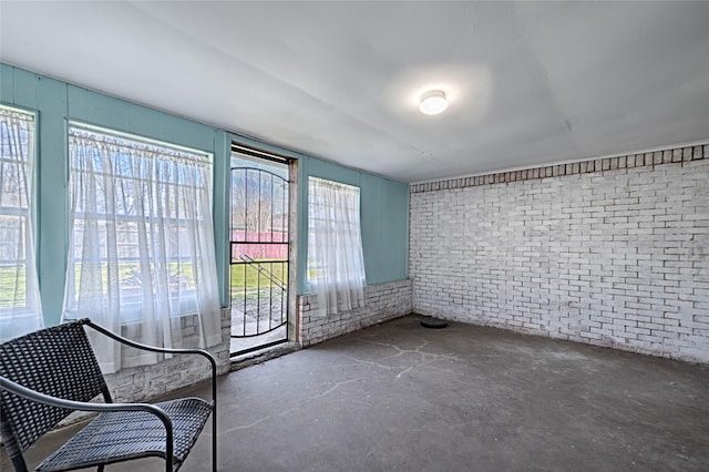 interior space with unfinished concrete floors and brick wall