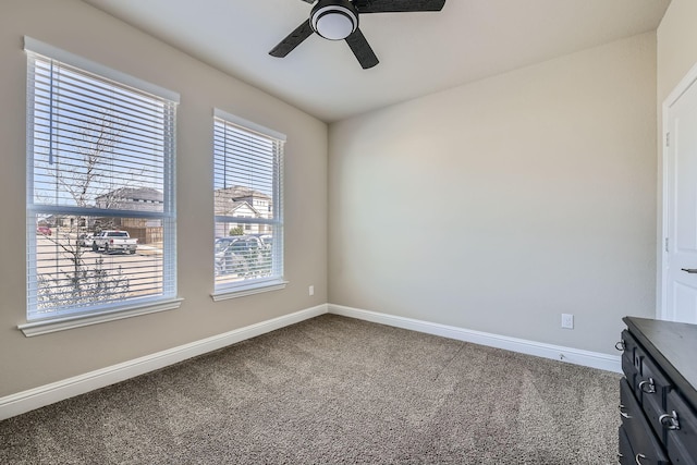 carpeted spare room with ceiling fan and baseboards