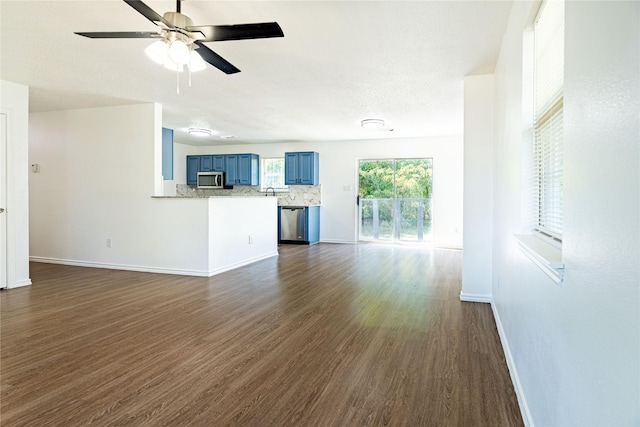 unfurnished living room with dark wood-style floors, a ceiling fan, and baseboards