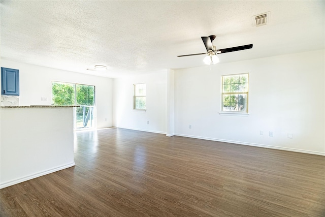 spare room featuring visible vents, baseboards, a textured ceiling, and dark wood finished floors