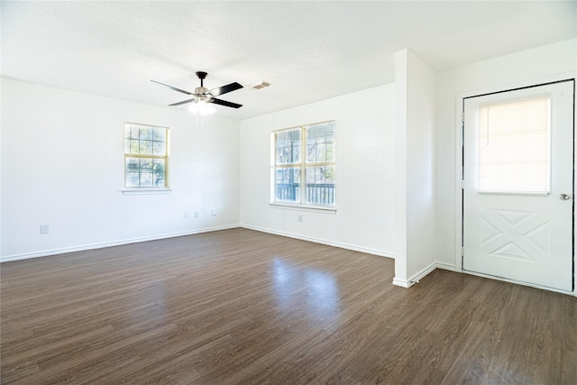 interior space featuring dark wood-style floors, visible vents, ceiling fan, and baseboards