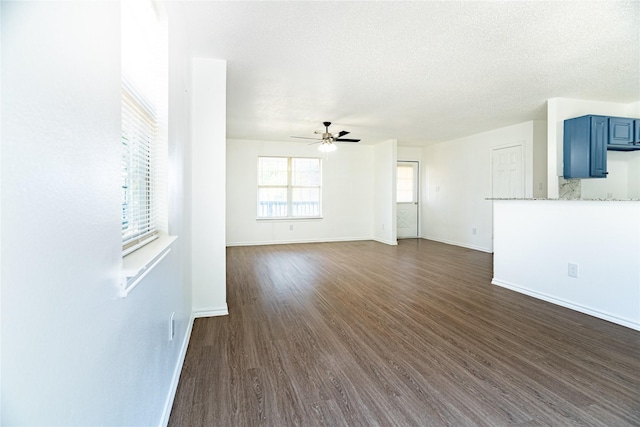 unfurnished living room with dark wood-style floors, a ceiling fan, baseboards, and a textured ceiling