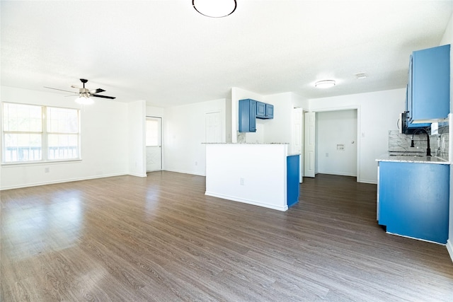 interior space with ceiling fan, baseboards, dark wood-style floors, and a sink