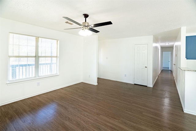 unfurnished room featuring visible vents, baseboards, ceiling fan, and dark wood-style flooring