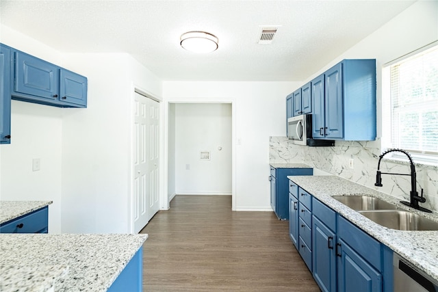 kitchen with blue cabinetry, visible vents, and a sink