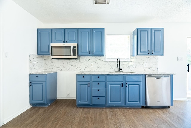 kitchen with dark wood finished floors, stainless steel appliances, blue cabinets, and a sink