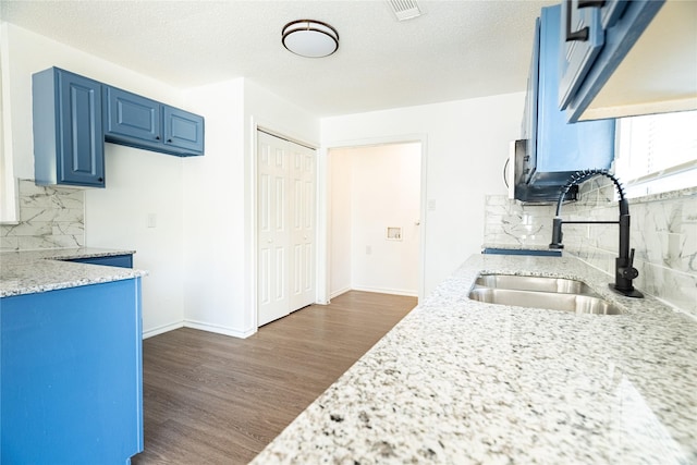 kitchen featuring a sink, baseboards, decorative backsplash, blue cabinets, and dark wood-style flooring