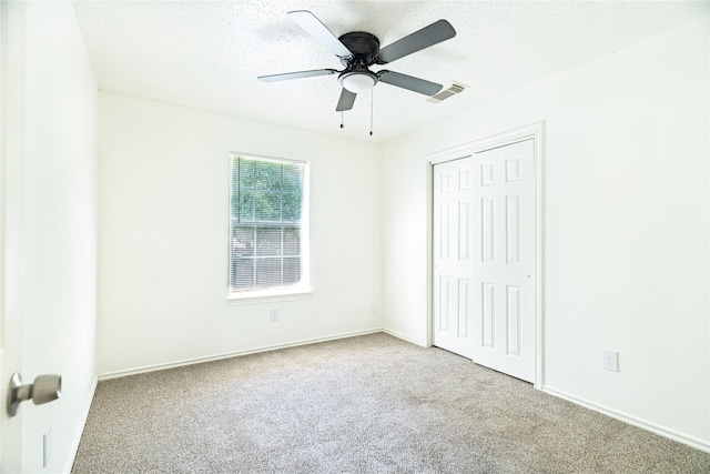 unfurnished bedroom with baseboards, visible vents, a closet, a textured ceiling, and carpet flooring