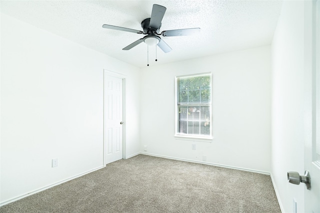 spare room with ceiling fan, carpet flooring, baseboards, and a textured ceiling